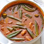 Okra stew is served in a white saucepan.