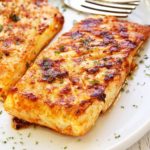 Grilled halibut is served on a white plate with a fork.