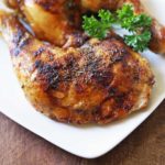 Chicken leg quarters are served on a white plate, garnished with parsley.