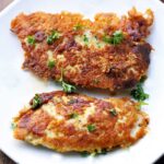 Parmesan chicken tenders are served on a white plate.