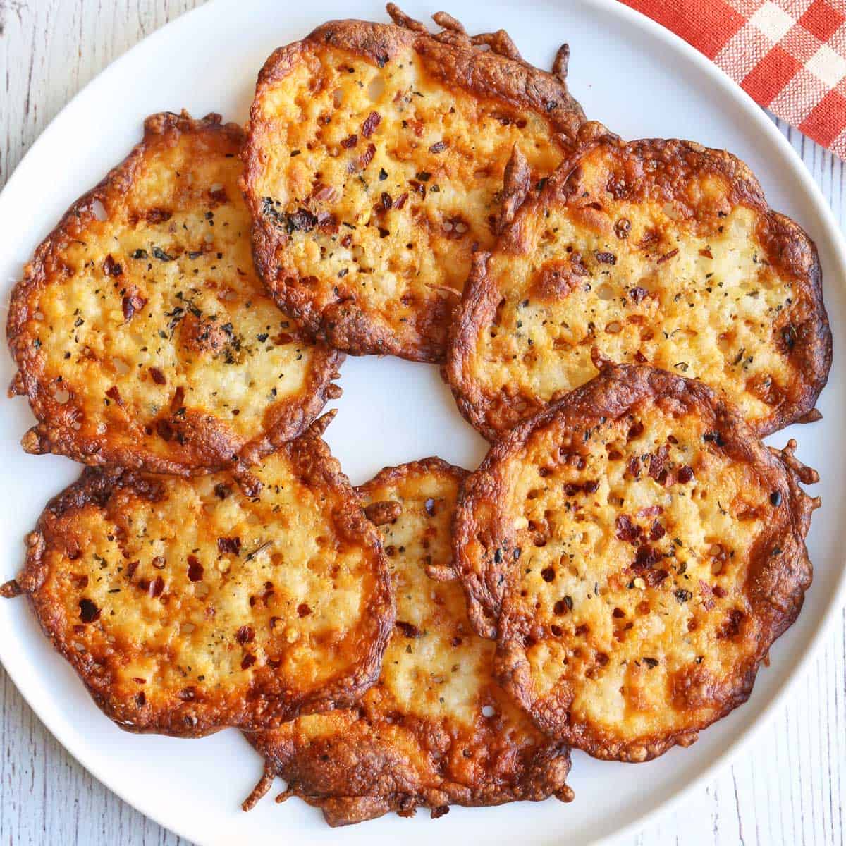 Keto cheese chips are arranged on a white plate.