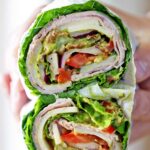 Lettuce sandwich os held in a person's hand.