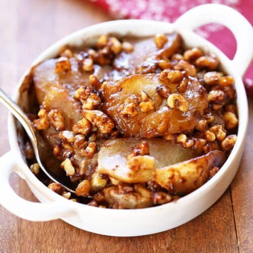 Keto apple crisp is served in a white bowl with a spoon.