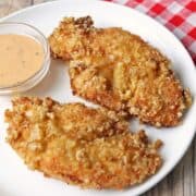 Pork rind chicken tenders are served with a dipping sauce.