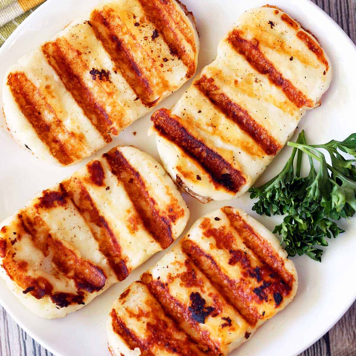 Grilled halloumi cheese is served on a white plate.