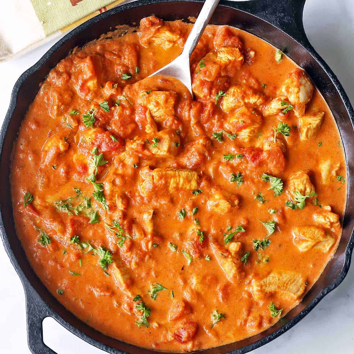 Keto butter chicken is served in a skillet with a spoon.