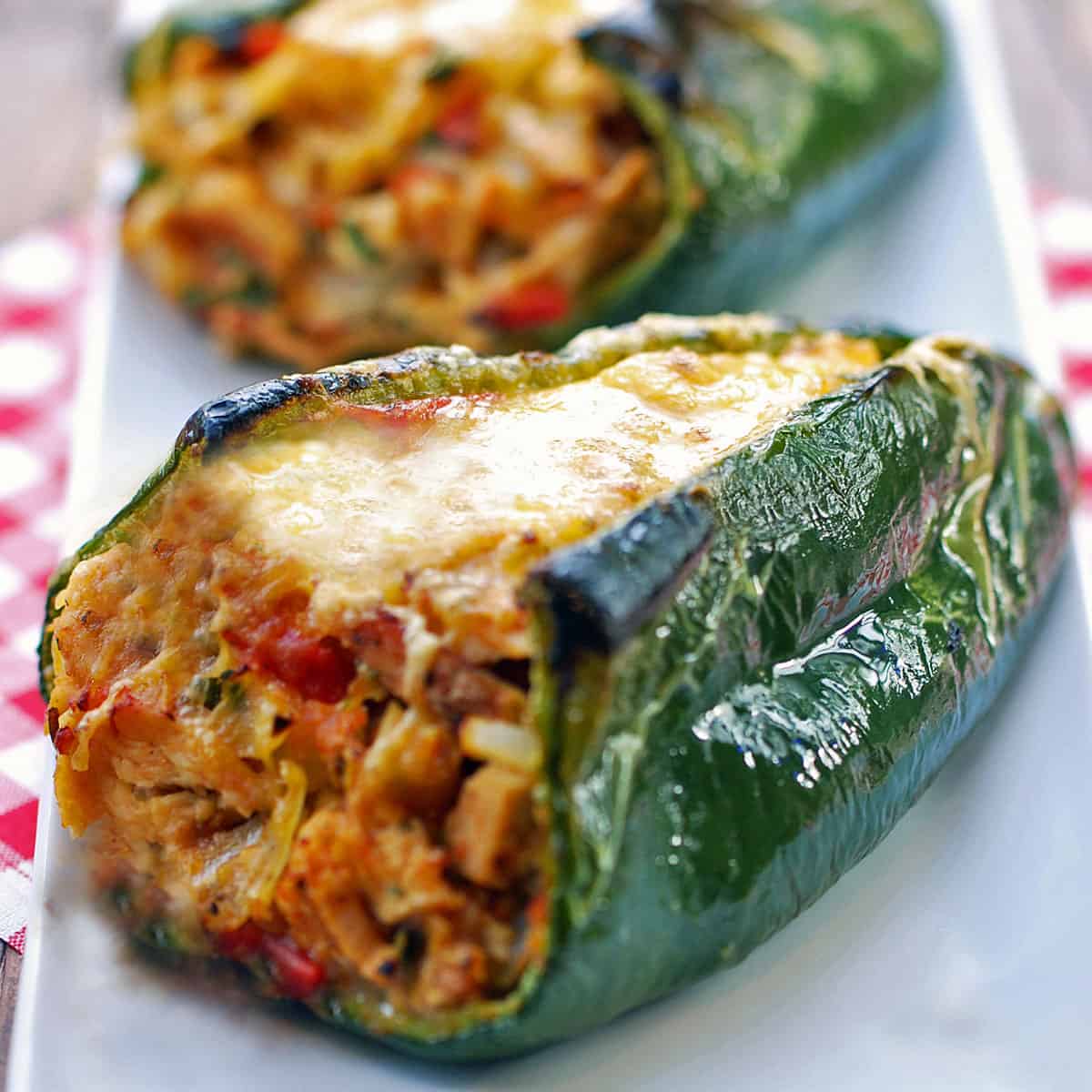 Stuffed poblano peppers are served on a white plate with a napkin.