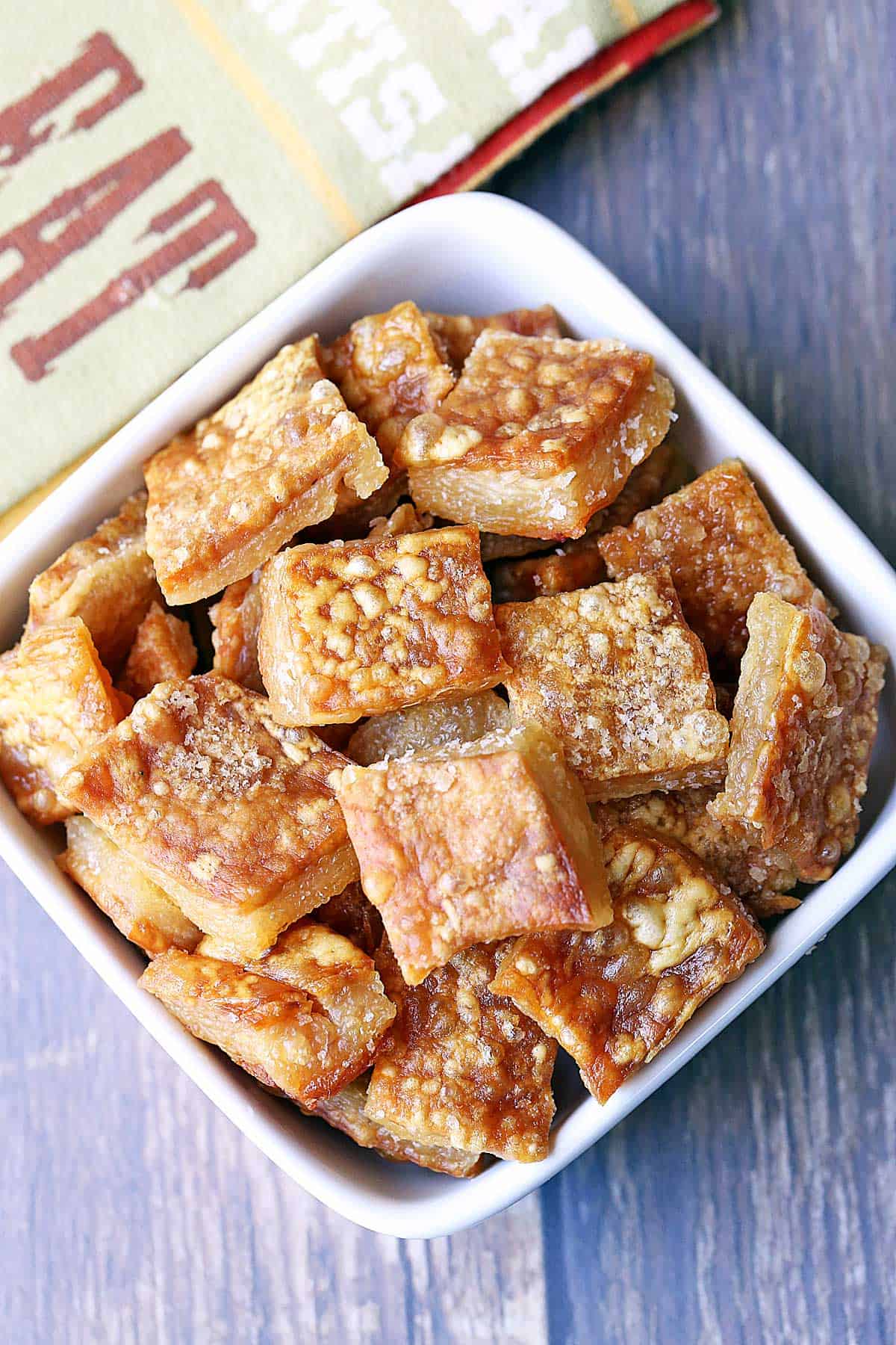 Homemade pork rinds are served in a white bowl. 