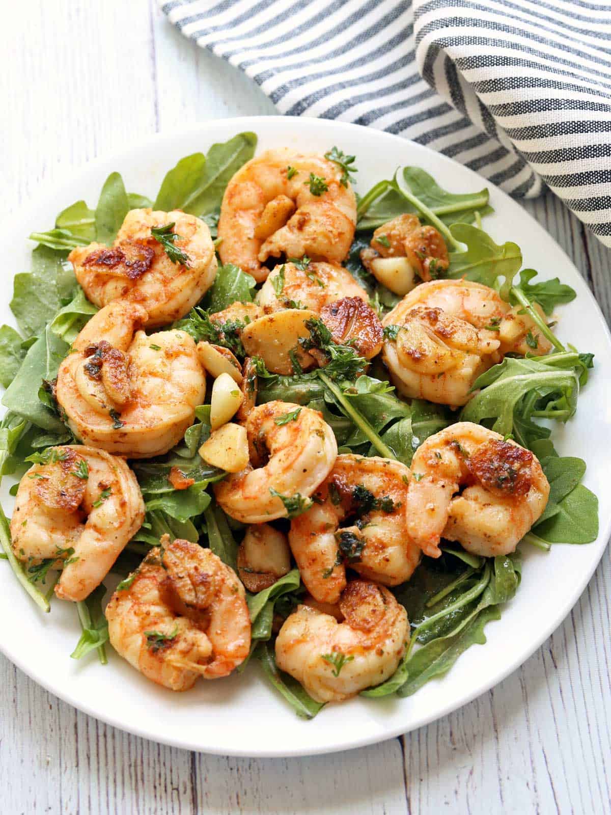 Garlic butter shrimp on a bed of arugula.