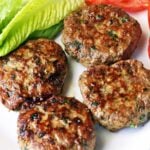 Turkey burgers are served with lettuce and sliced tomatoes.