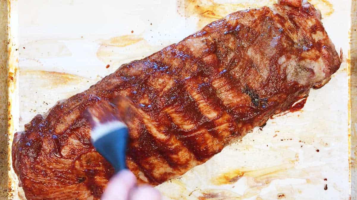 Brushing ribs with bbq sauce.