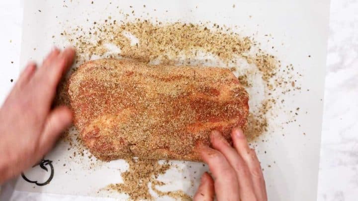 Seasoning the pork shoulder.