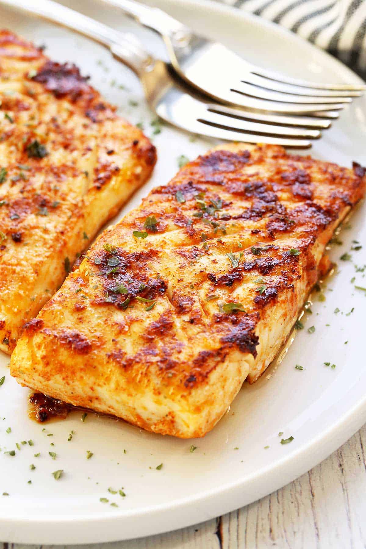 Grilled halibut fillets served on a white plate. 
