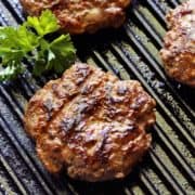 Grilled burgers are photographed on the grill.