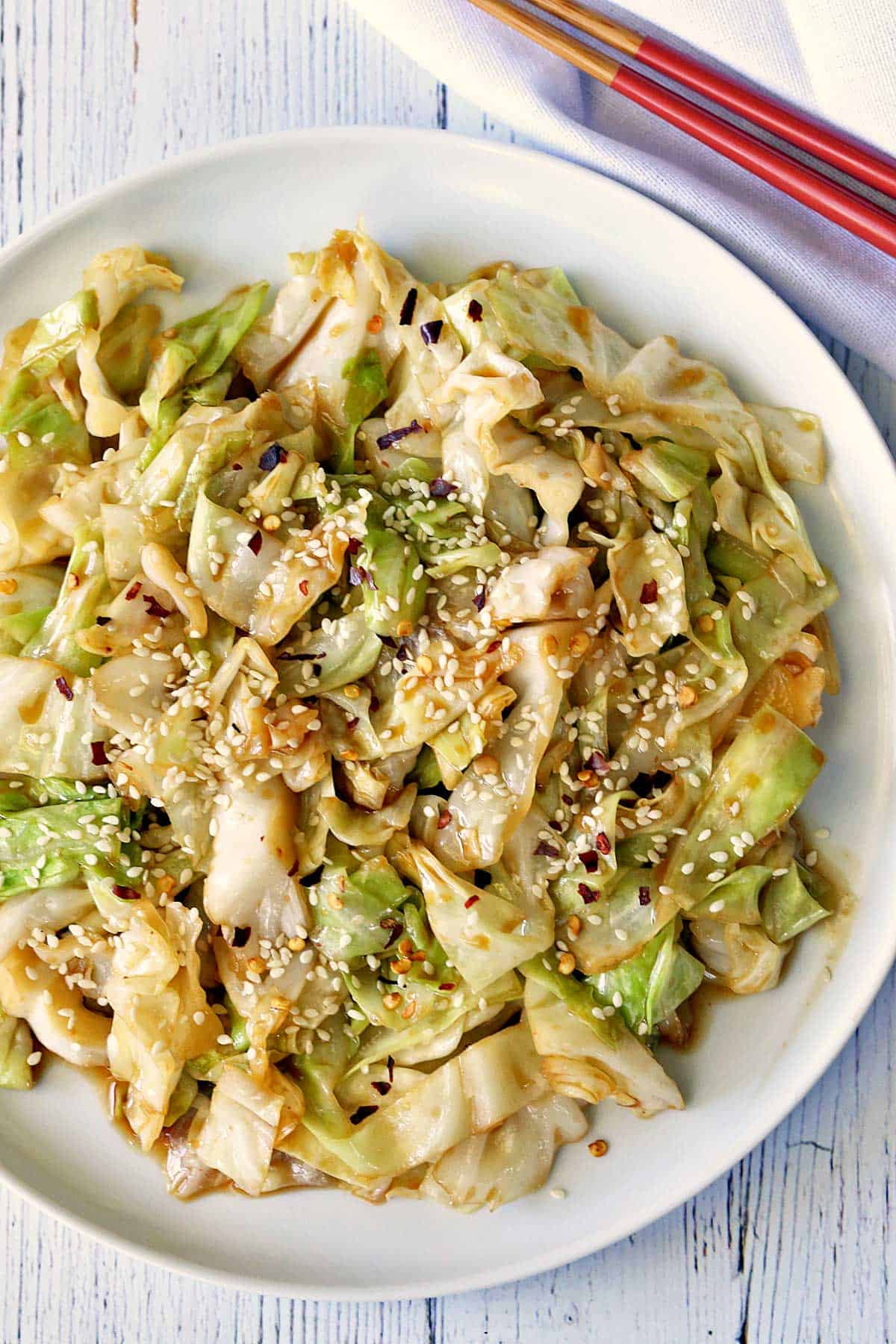 Cabbage stir fry is served with chopsticks. 