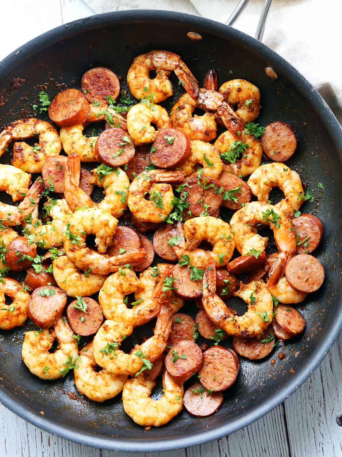 Shrimp and sausage are served in a skillet.