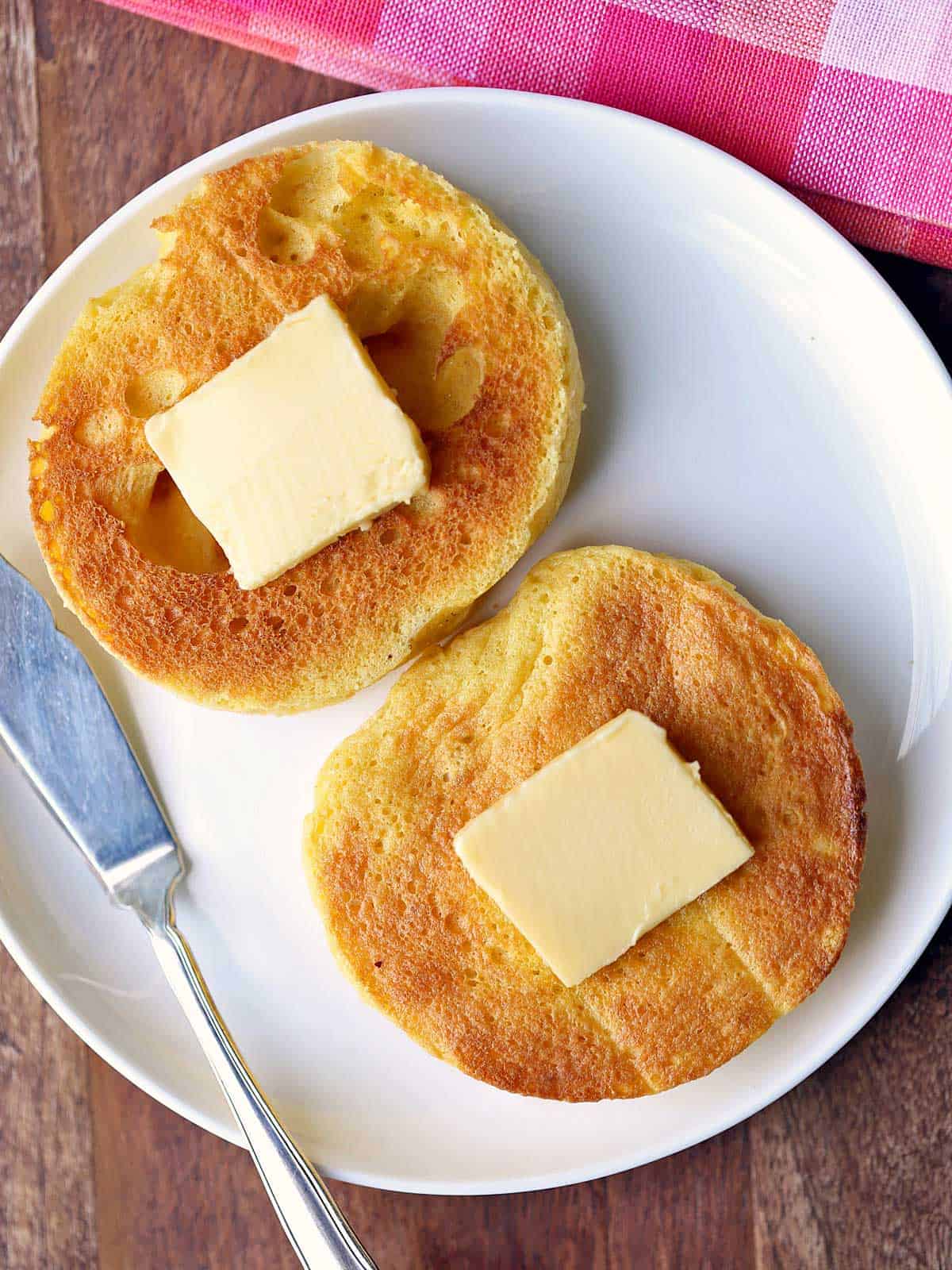 Keto English muffin is served with butter and a butter knife. 