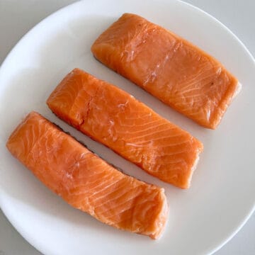 Three salmon fillets on a plate. They don't have bones.