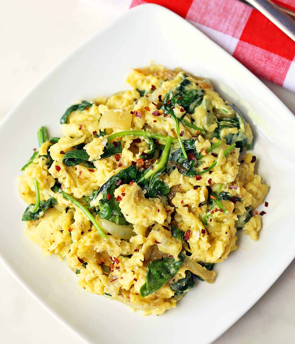 Spinach and eggs are served on a white plate. 