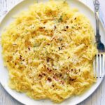 Spaghetti squash pasta is served on a white plate with a fork.