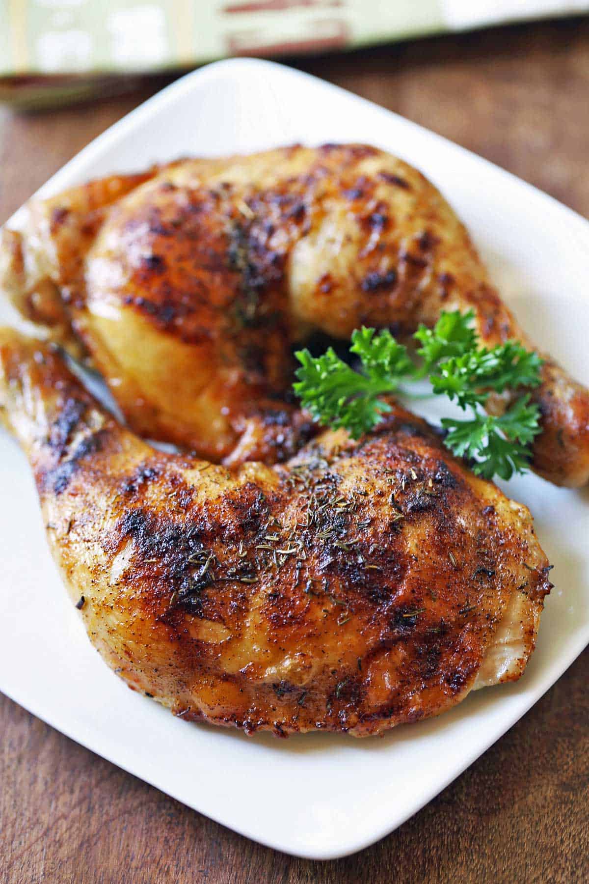 Two chicken leg quarters are served on a white plate.