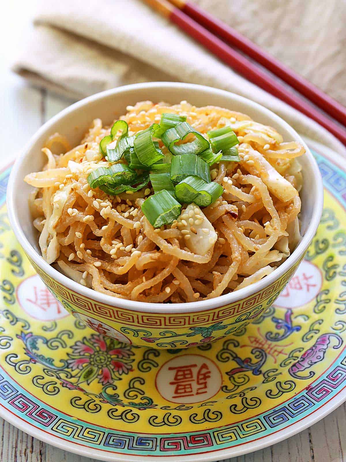 Shirataki Sesame Noodles topped with scallions and served with chopsticks.