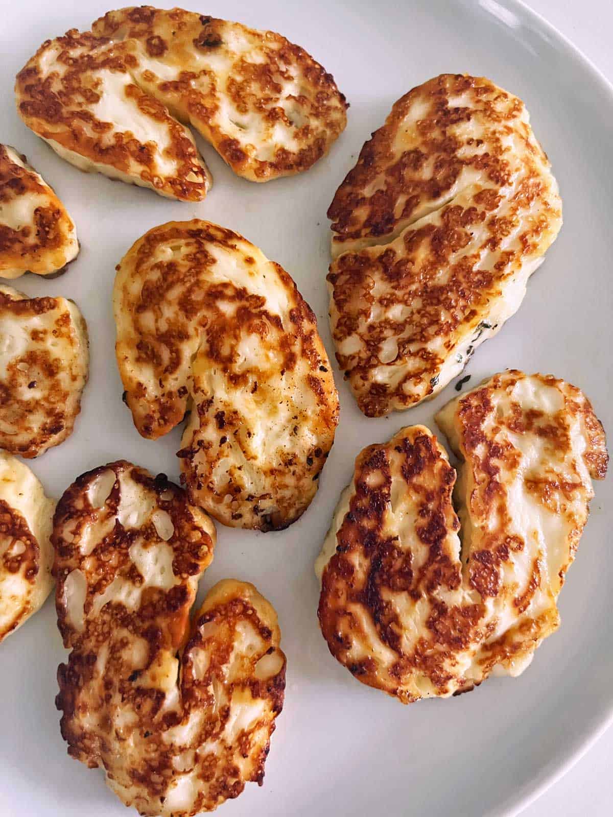 Pan-fried halloumi cheese on a white plate.