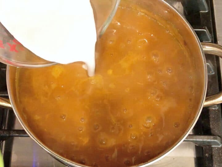 Adding coconut milk to the soup.
