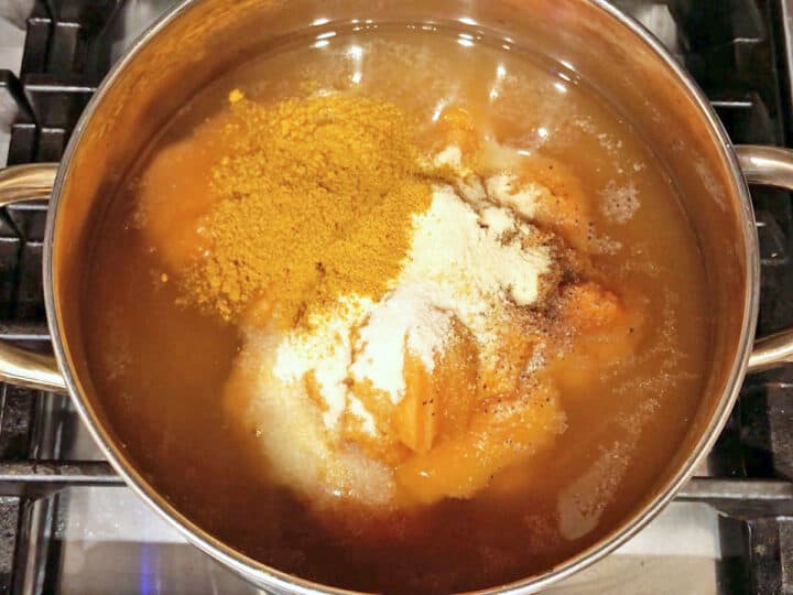 Pumpkin curry soup ingredients in a stockpot.
