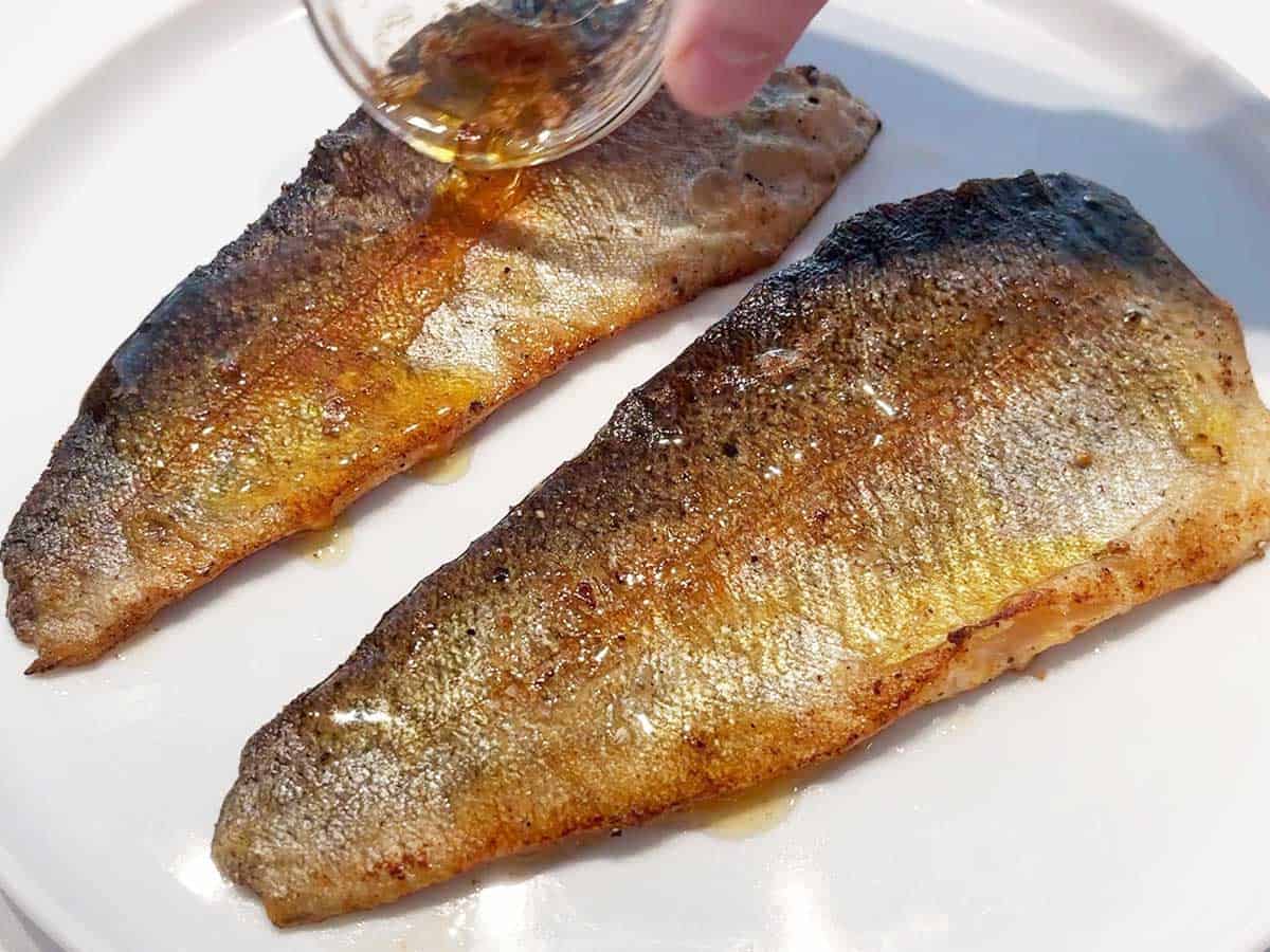 Drizzling cooked rainbow trout with pan juices.