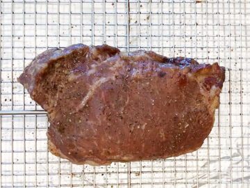 The steak in the pan after baking in the oven and before searing.