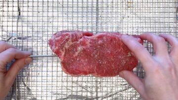 Inserting a meat thermometer probe into the steak.