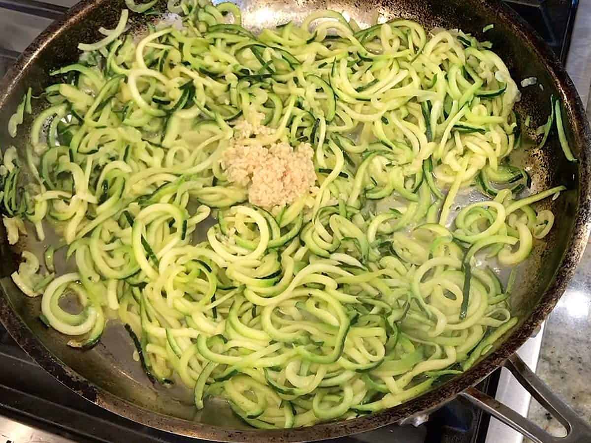 Adding garlic to zoodles.