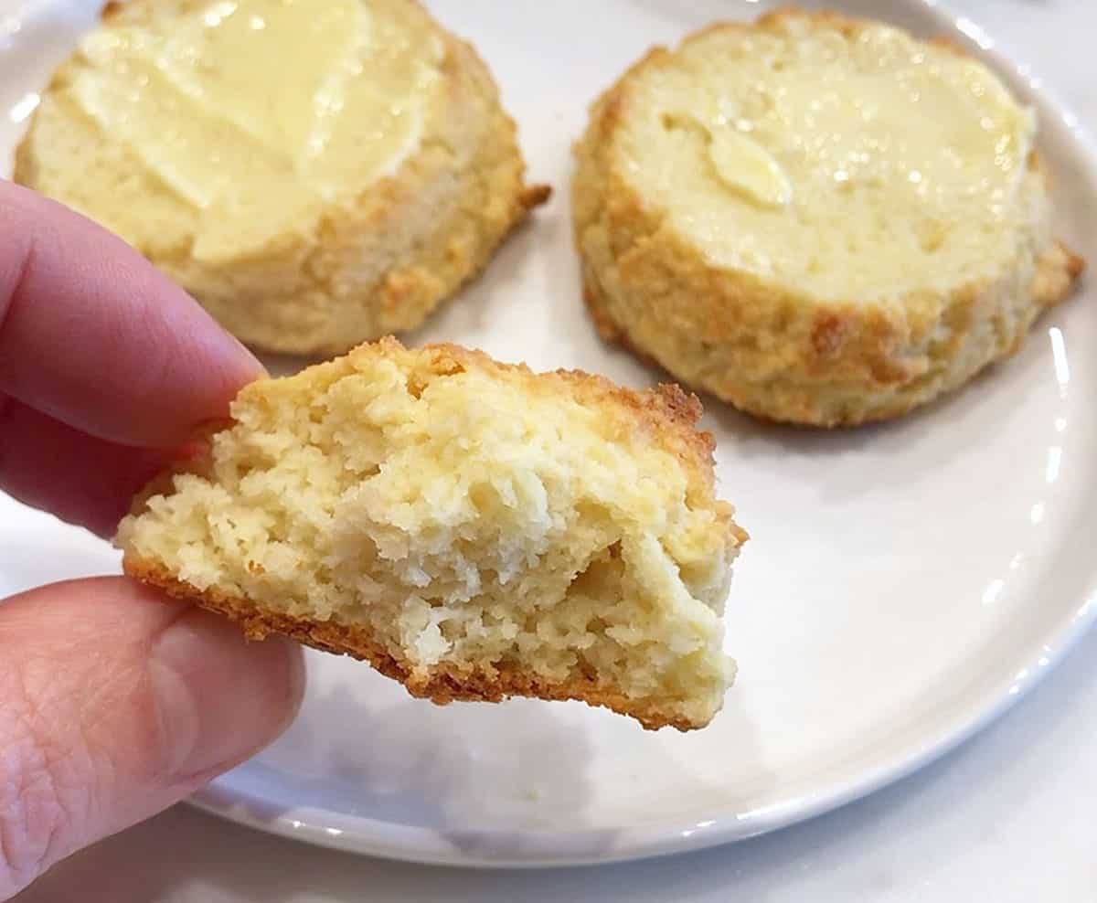 A hand holding a fluffy keto biscuit.
