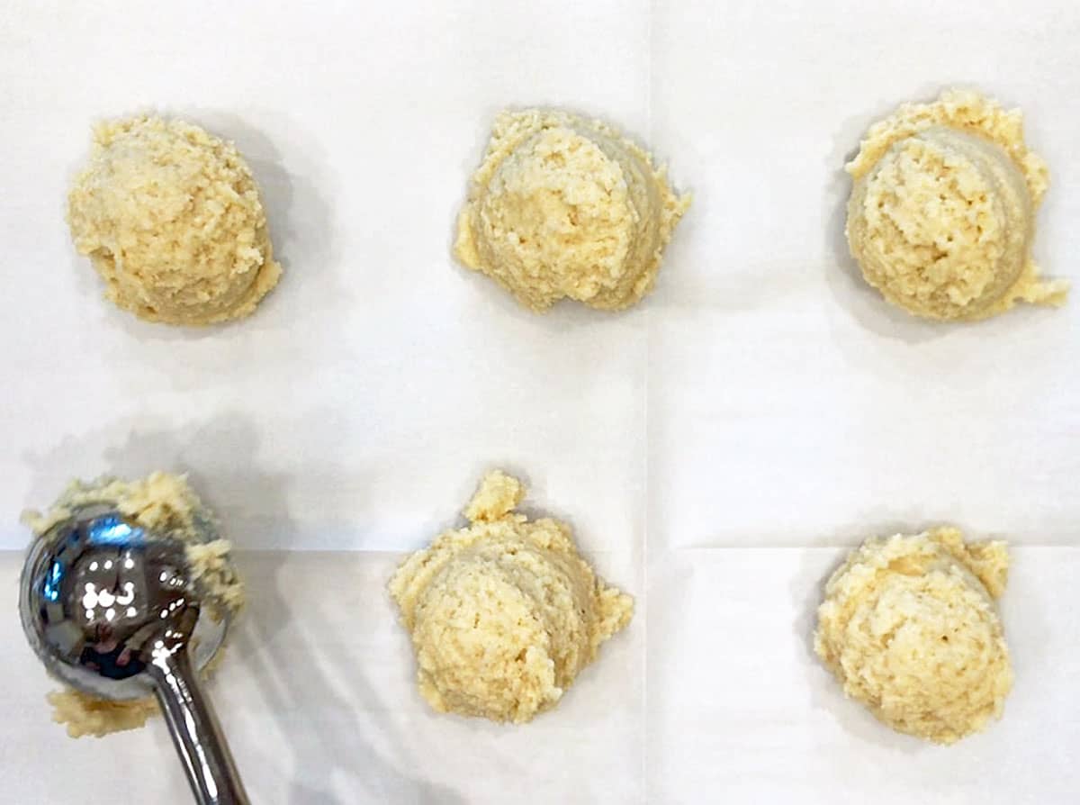 Scooping keto biscuits onto baking sheet.