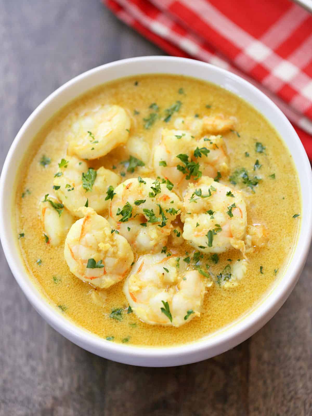 Shrimp curry is served in a white bowl with a red napkin.