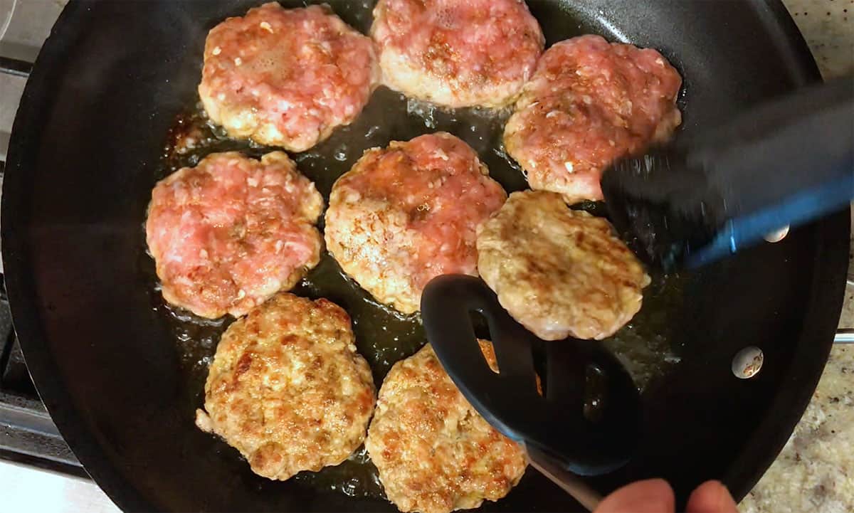 Flipping the patties in the skillet.