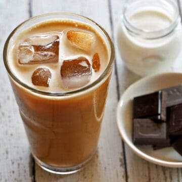 Iced coffee is served in a tall drinking glass.