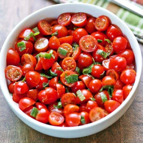 Tomato salad is served in a white bowl.