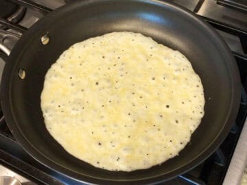 Cheese is melting in a skillet.