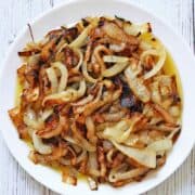 Sauteed onions are served on a white plate.