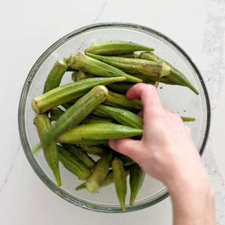 Coating the okra with olive oil and spices.