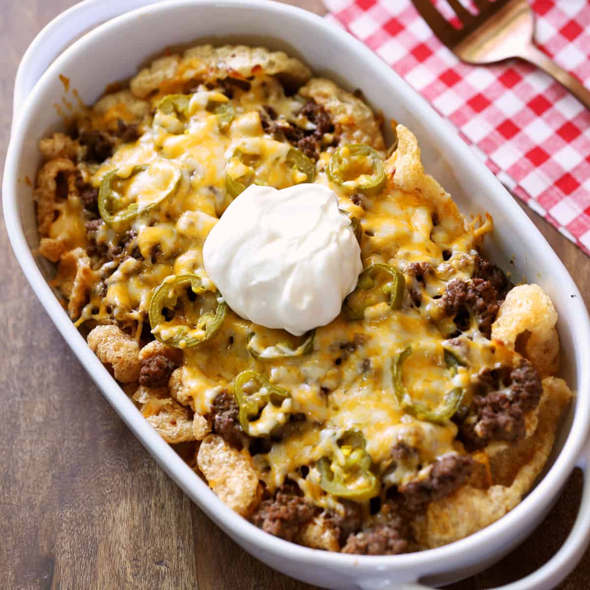 Keto nachos are served in a baking dish and topped with sour cream.