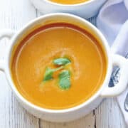 Pumpkin curry soup is served in a white bowl.