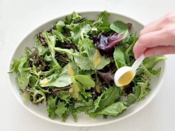 Dressing the mixed greens with half the vinaigrette.