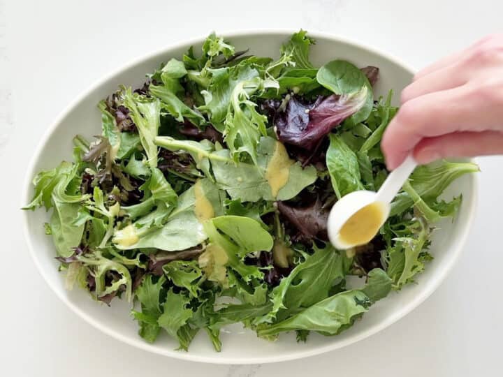 Dressing the mixed greens with half the vinaigrette.