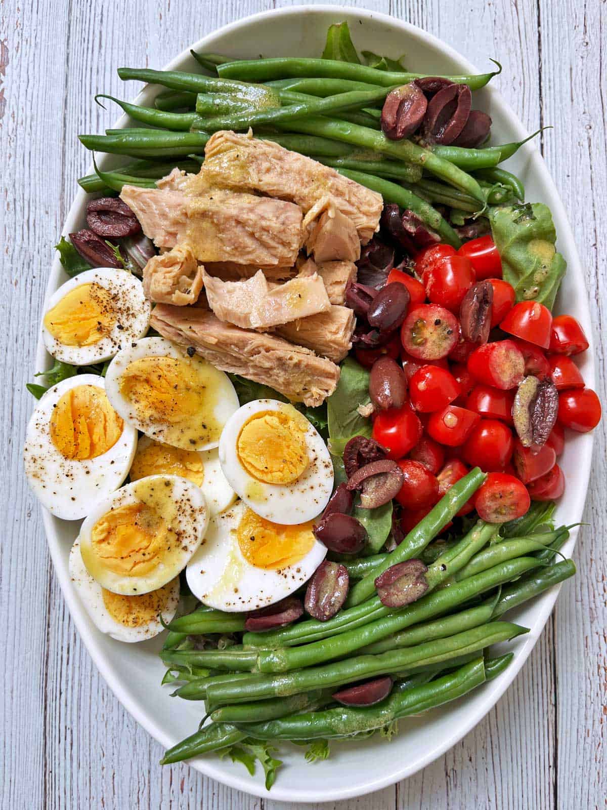 Nicoise salad is served on a white serving platter.
