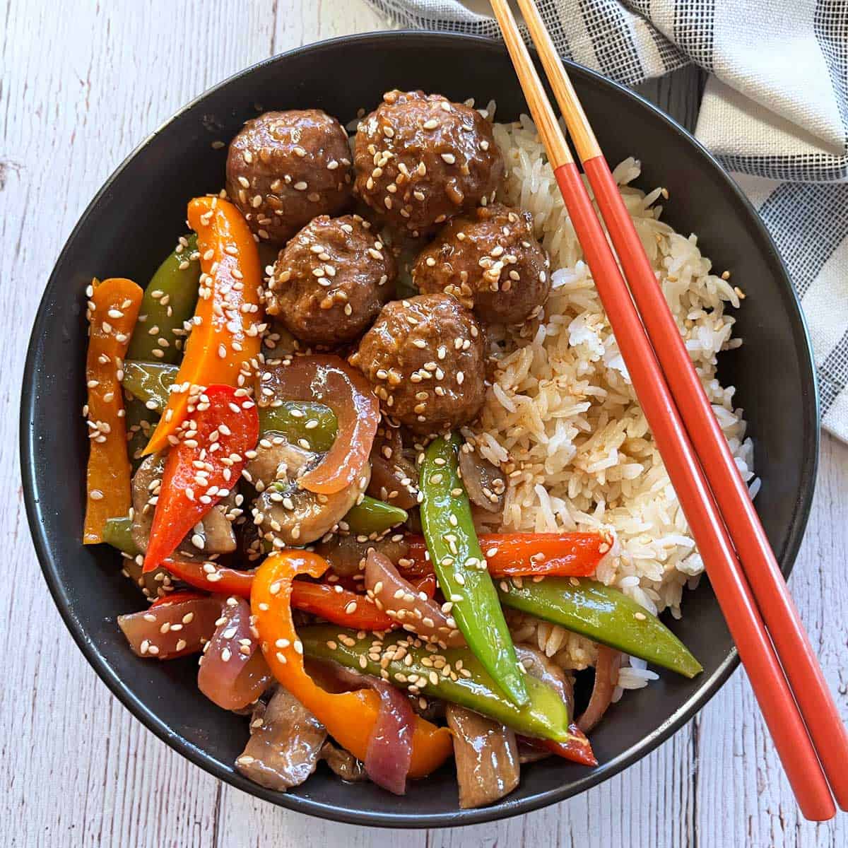 Asian meatballs and vegetable stir-fry are served with rice.