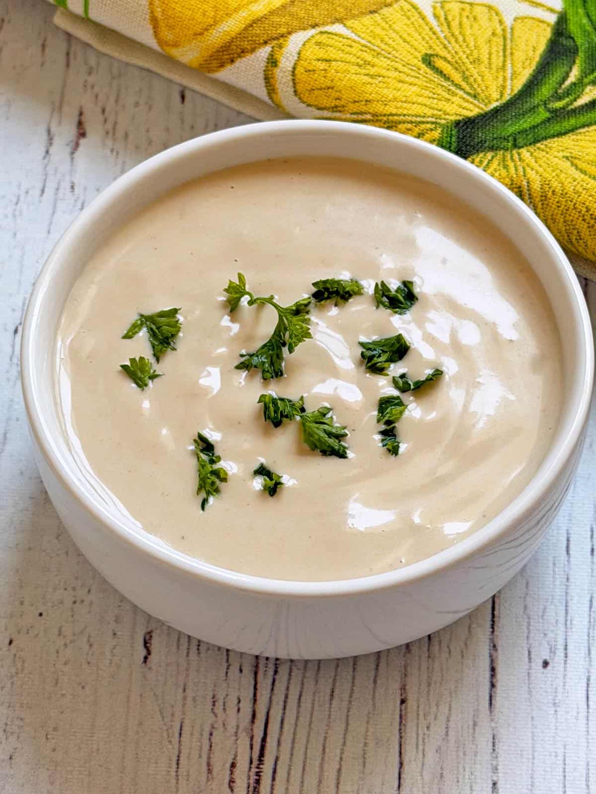 Tahini sauce is served in a white bowl.