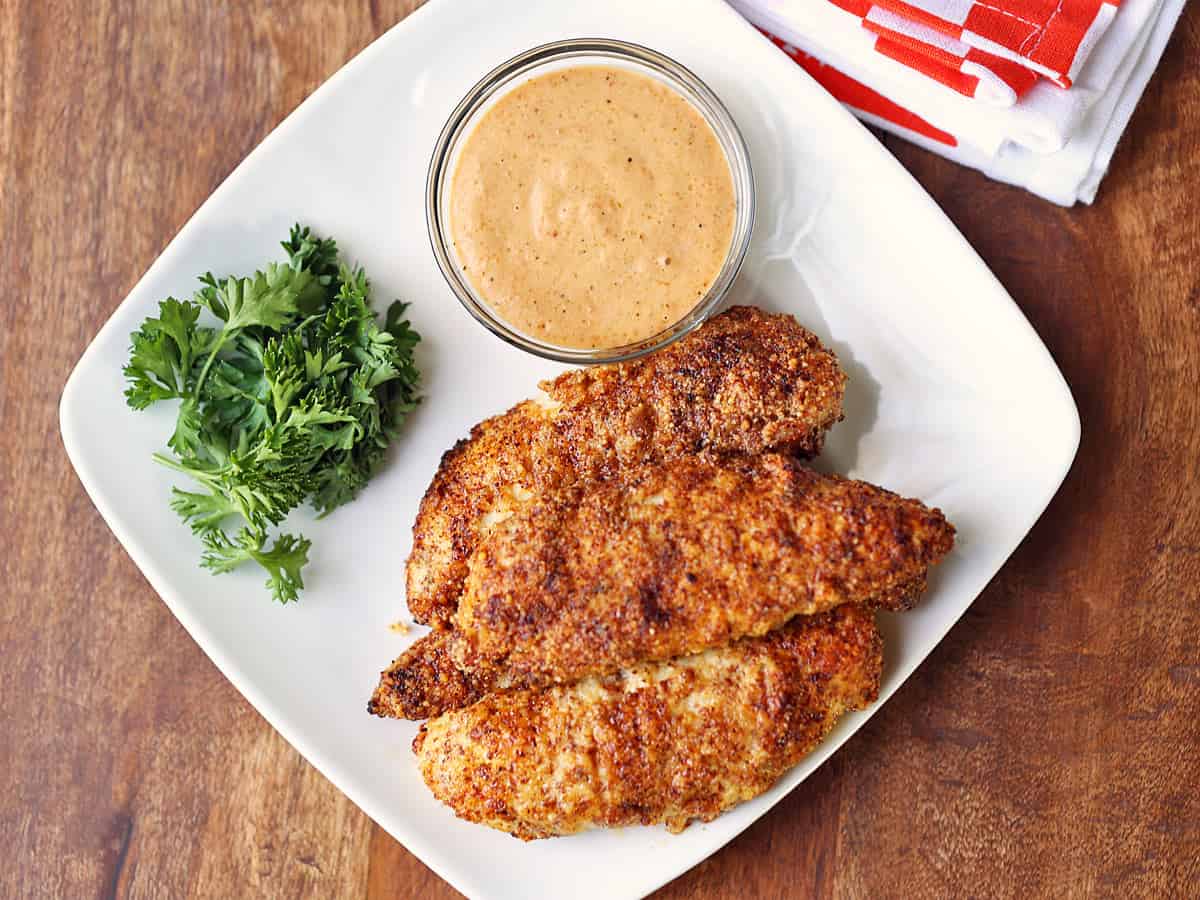 Almond flour chicken tenders are served with a dipping sauce.